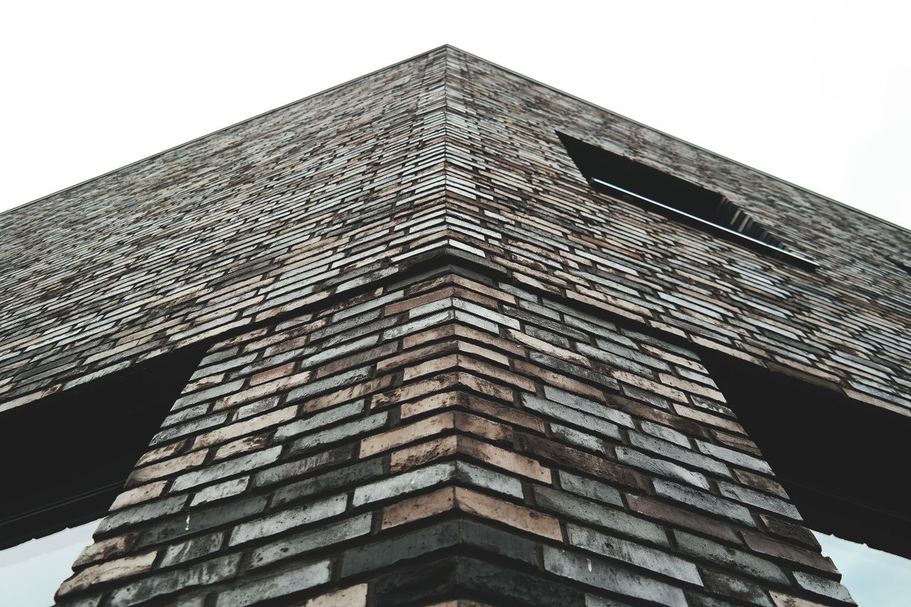 Home Low-angle view of a modern brick building with large glass windows against a clear sky.